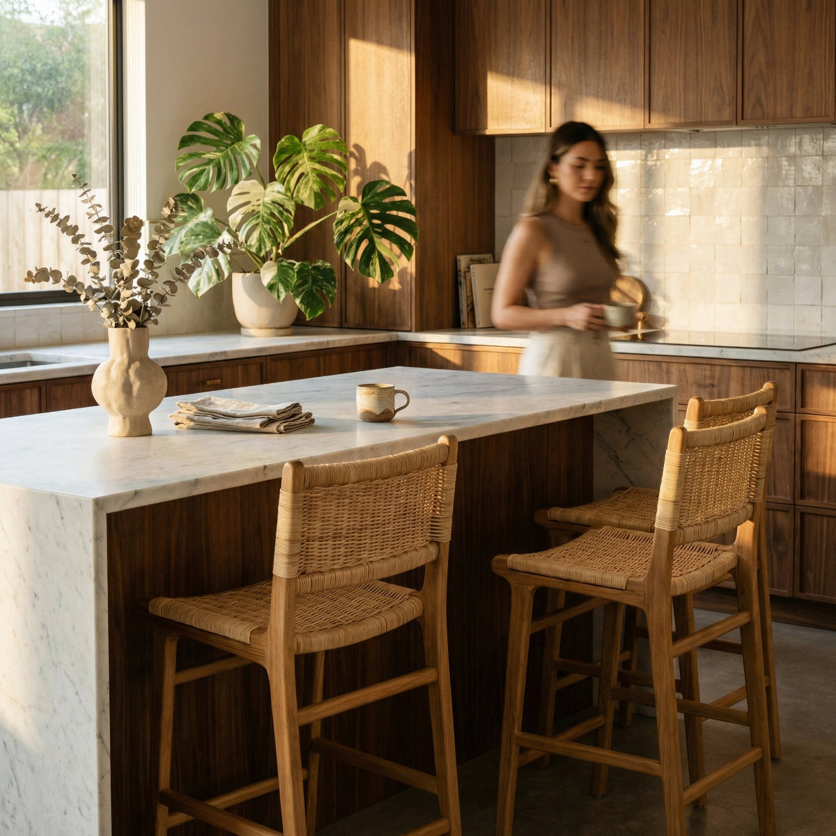 Modern kitchen with wooden island, stools, and a woman in the background