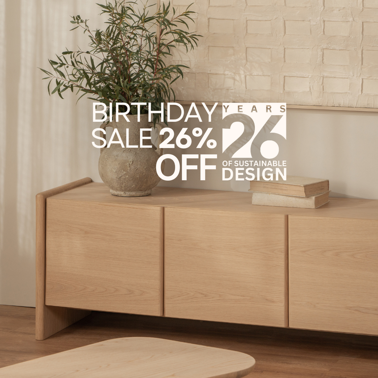 Wooden sideboard with a plant and books, promotional text overlay for a birthday sale.