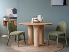 Round wooden dining table with green chairs