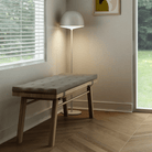 Bench with cushion, floor lamp and window.