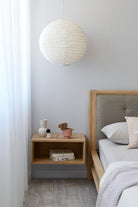 Bedroom with paper lantern, nightstand, and bed.