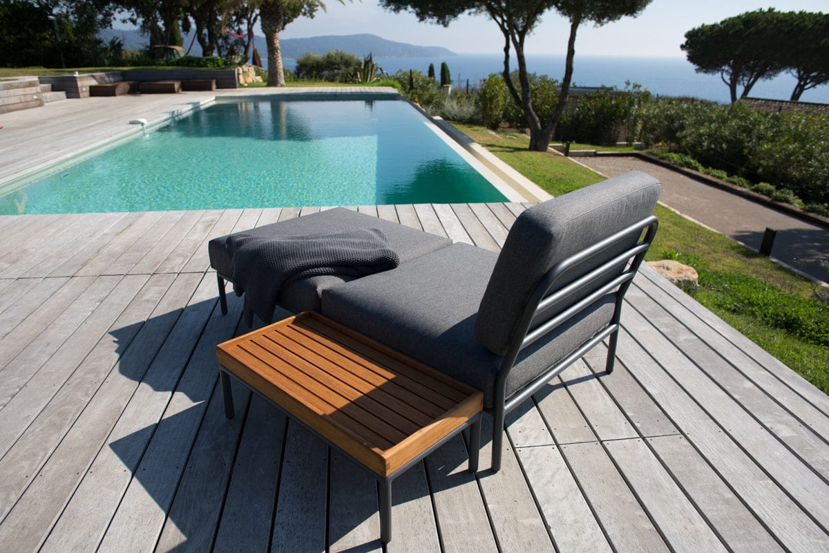 Dark grey chair and ottoman with bamboo side table by pool.