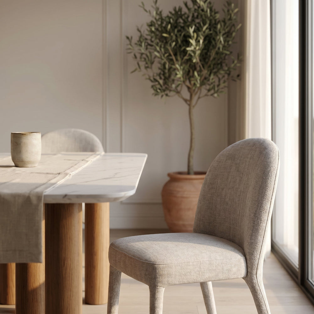 Dining area with wooden table, gray chair, and potted plant in a bright room.