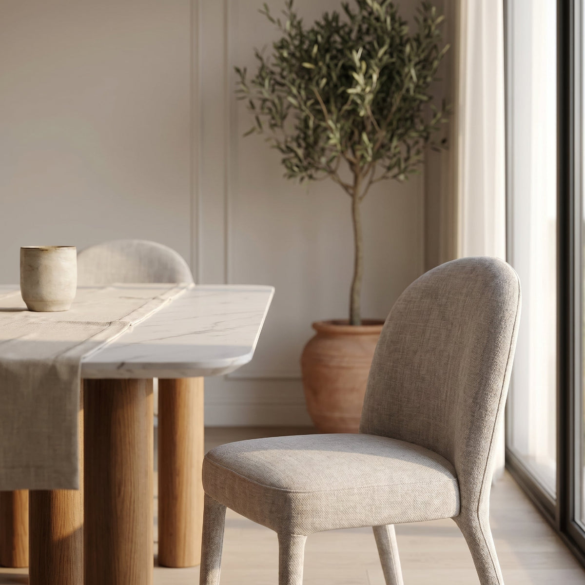 Dining area with wooden table, gray chair, and potted plant in a bright room.