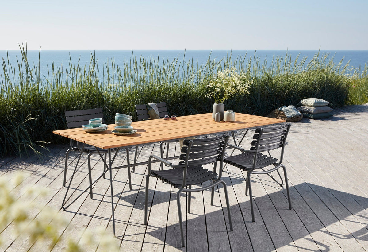 ReCLIPS dark grey dining table and chairs on a deck overlooking the ocean.