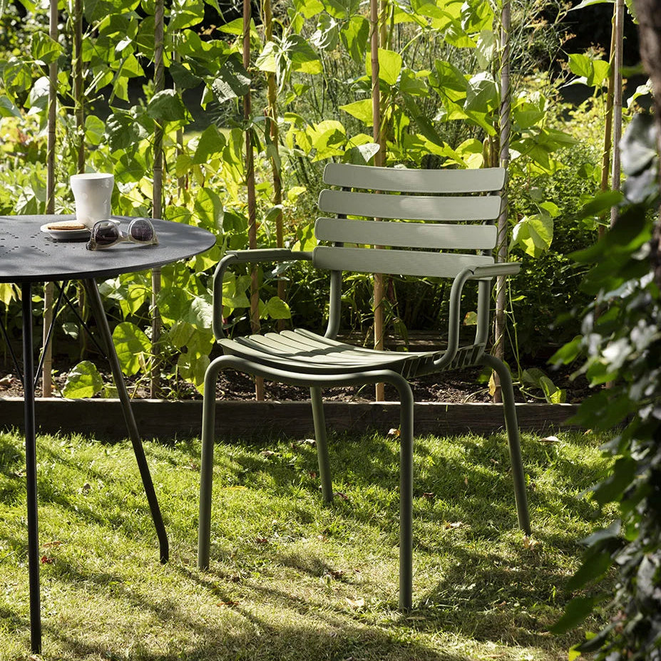 Garden scene with a chair, table, and cup under a tree
