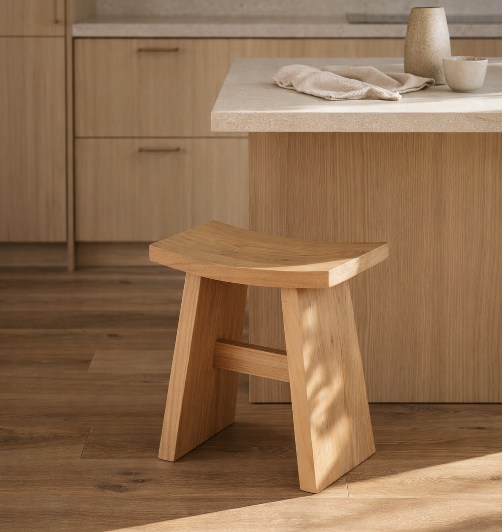Wooden stool in a kitchen setting with light wood cabinets and a countertop.