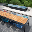 Outdoor dining table with no-arm chairs near pool.