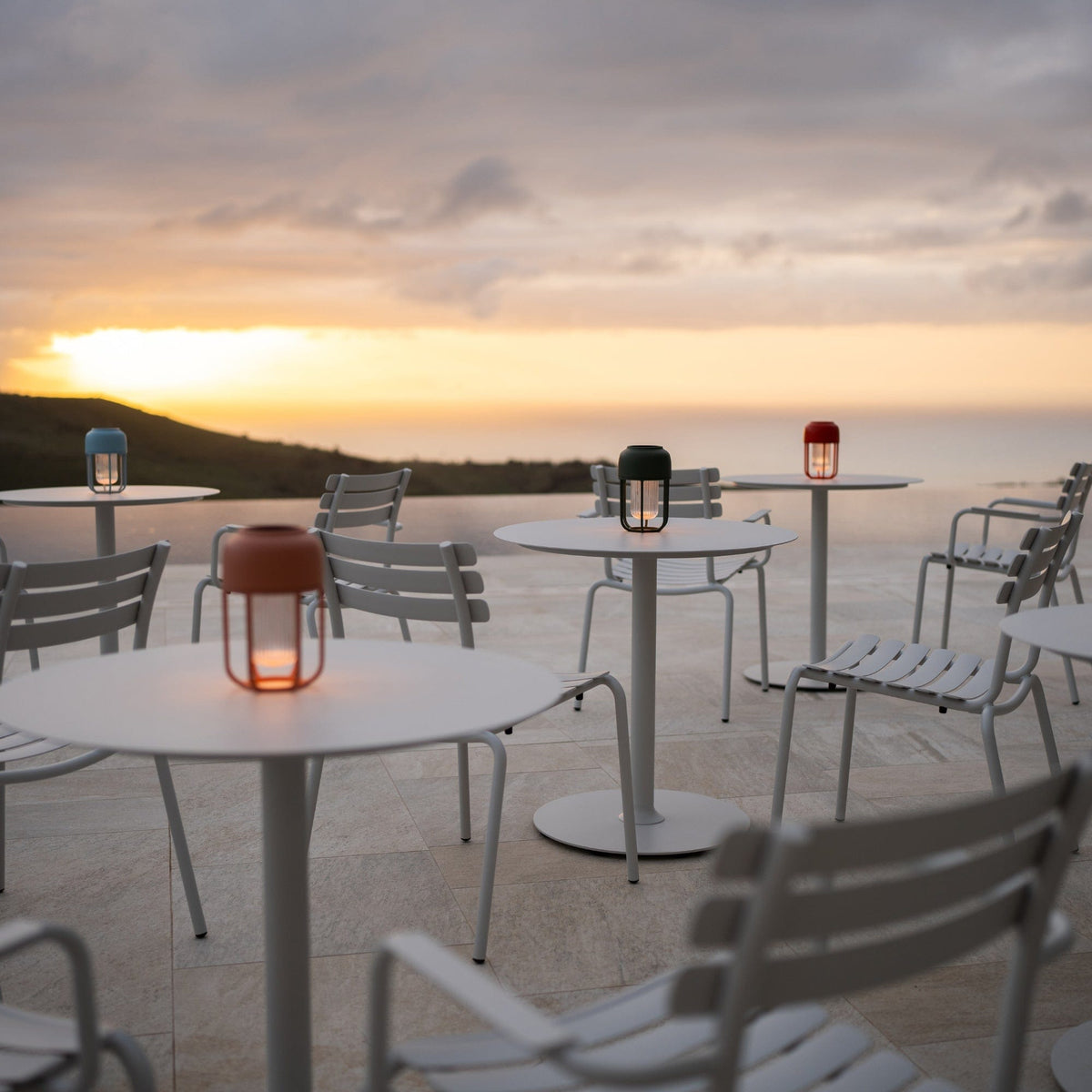 White outdoor tables with pico alua lanterns at sunset
