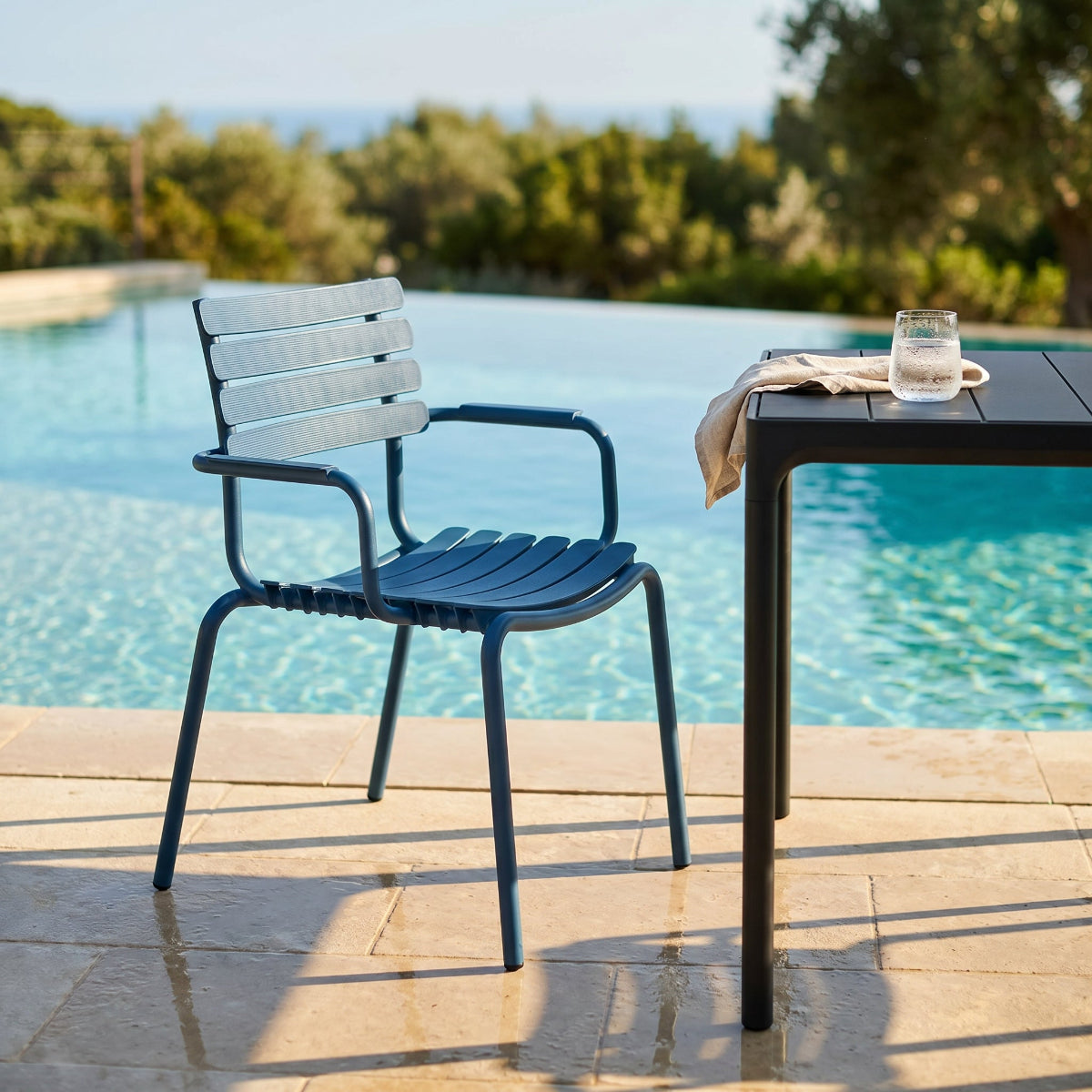 Blue outdoor chair and table by a pool with a scenic background