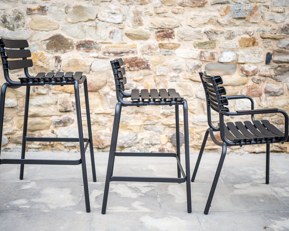 Black reclips dining chairs against stone wall