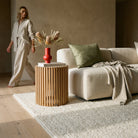 Living room with a beige sofa, wooden side table, and decorative elements.