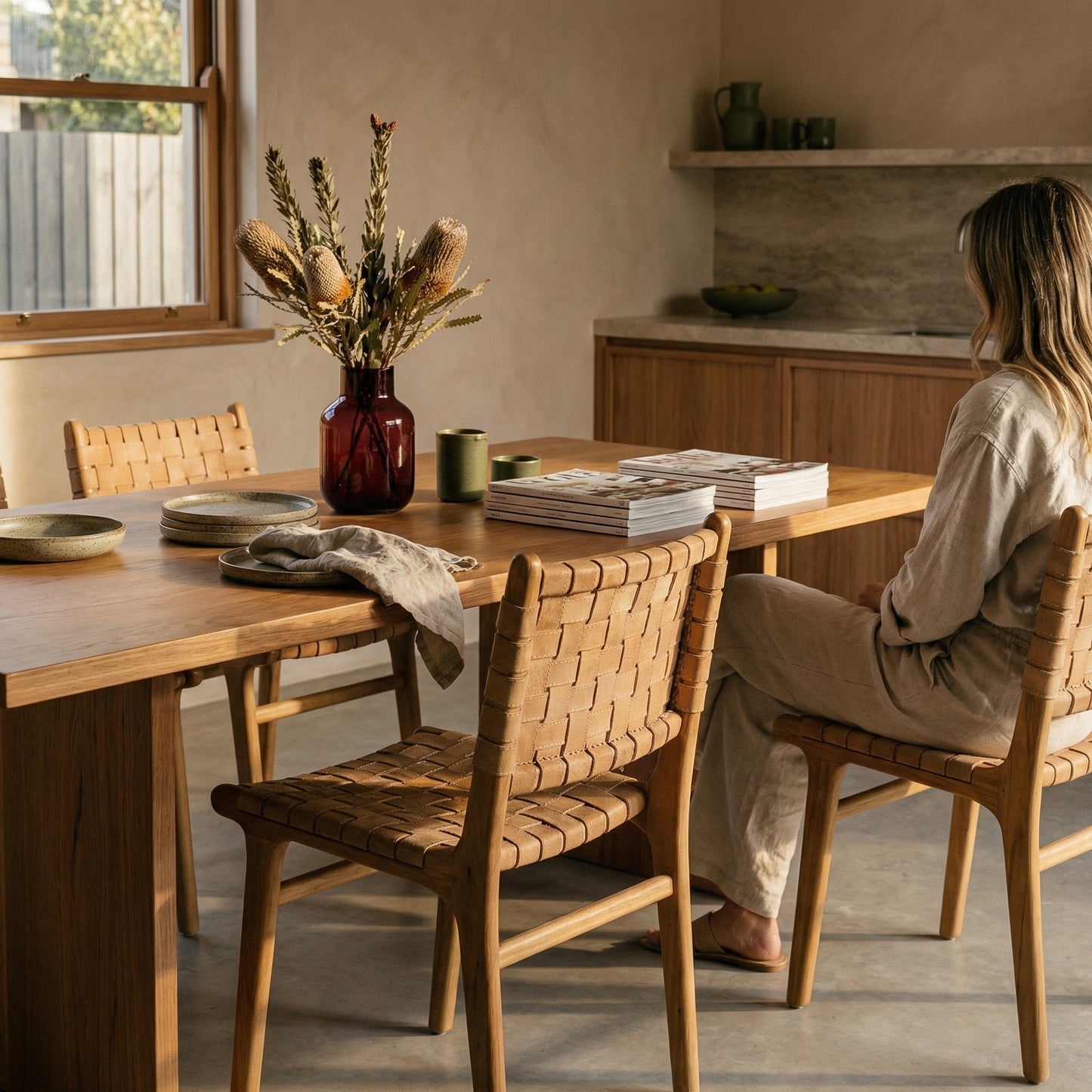 Woman sitting at a wooden dining table in a cozy kitchen.