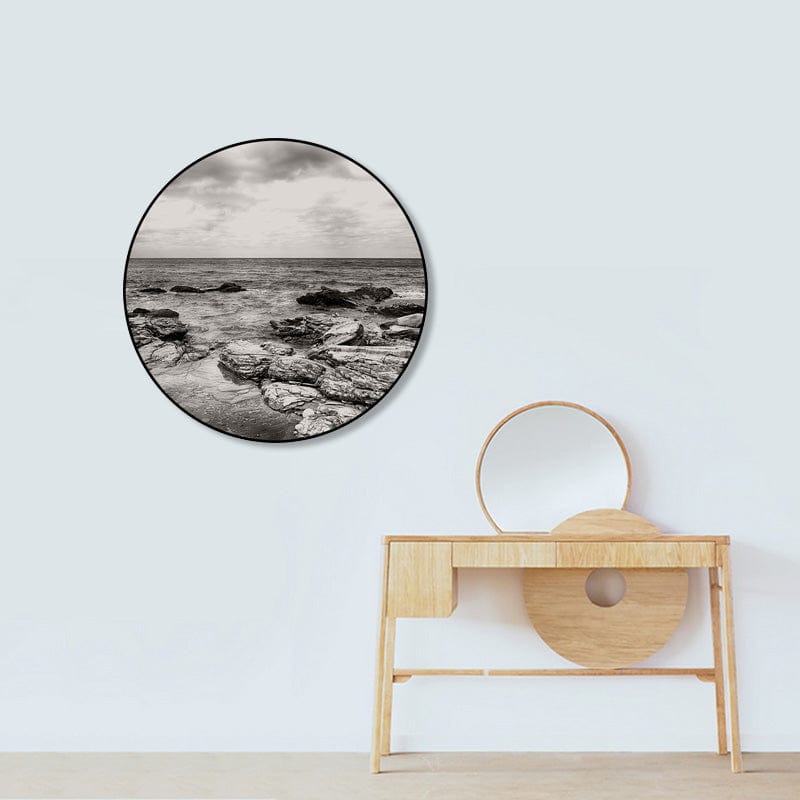 Black and white seascape in round frame over wooden vanity.