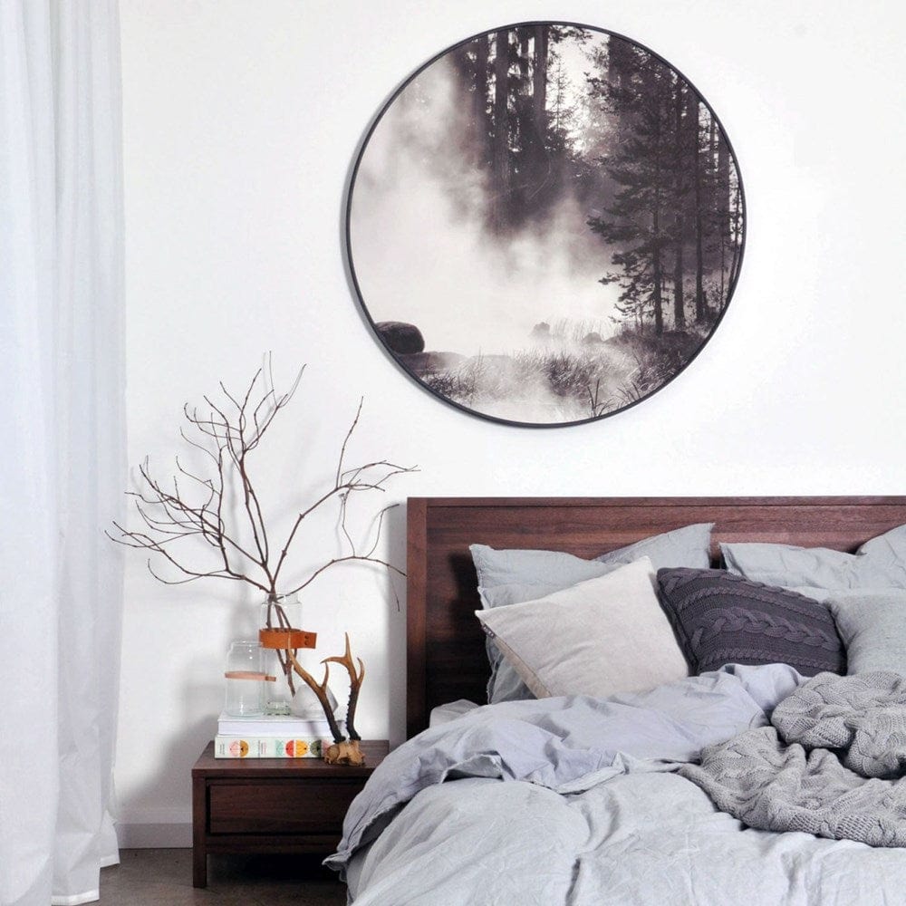 Black & white forest scene in round frame over bed