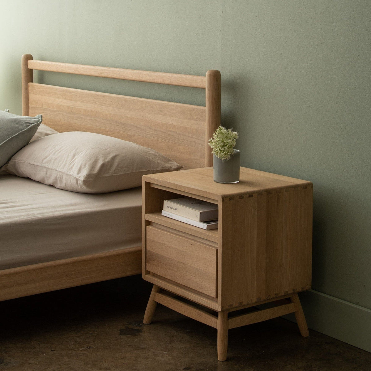 Wooden bedside table with drawer and bed