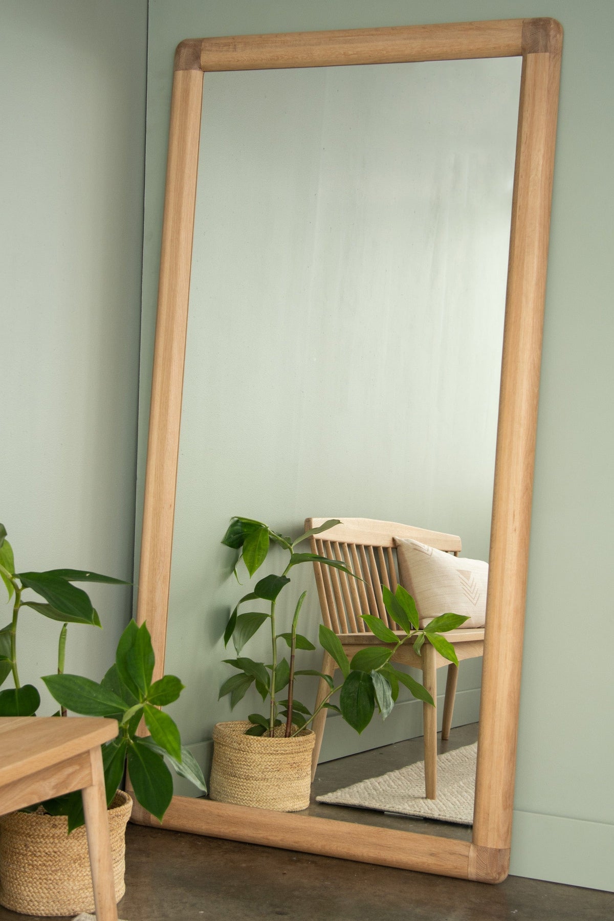 Wooden framed leaning mirror with plants and chair