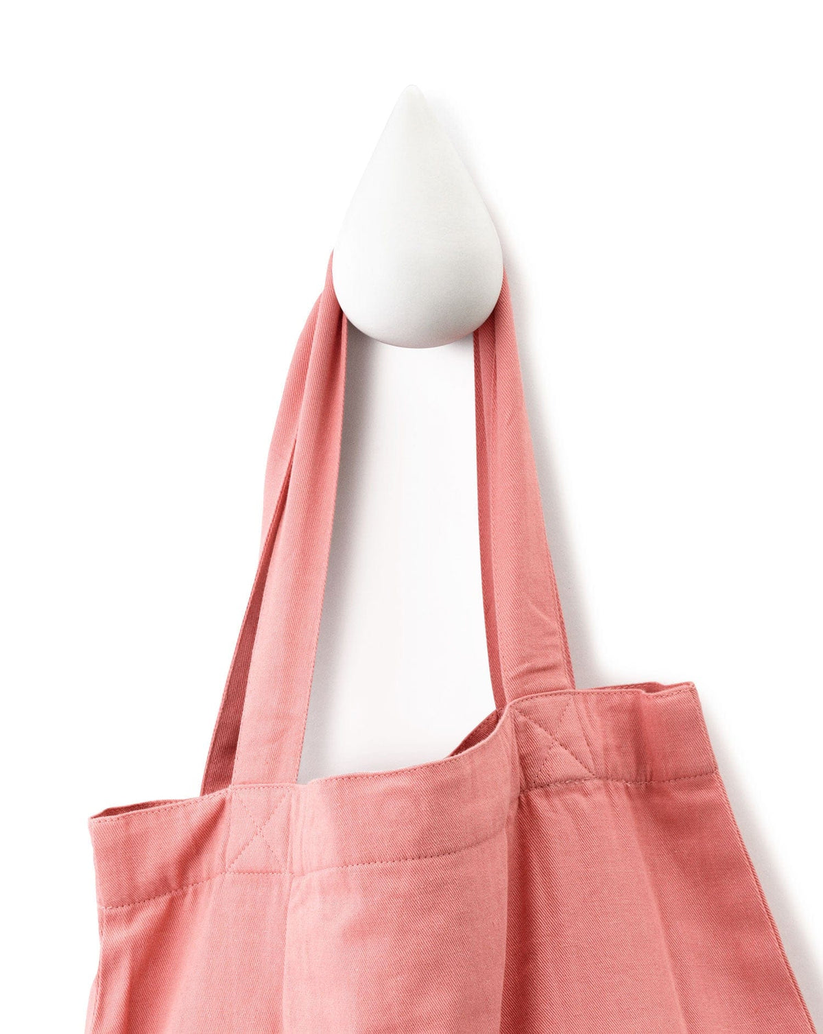 Pink tote bag hanging on white wall hook
